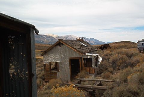 1986 Ford Bronco - A van is visible in the distance, parked near dilapidated structures in a remote, arid landscape.