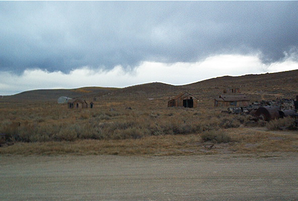 Desert landscape with abandoned wooden buildings under a cloudy sky