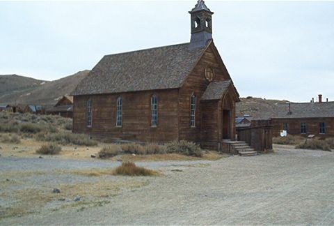 1986 Ford Bronco - A historic wooden church stands in a desolate ghost town setting, with barren hills visible behind it.