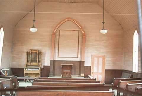 1986 Ford Bronco - The interior of a rustic church features wooden pews, a pipe organ, and a pulpit area.