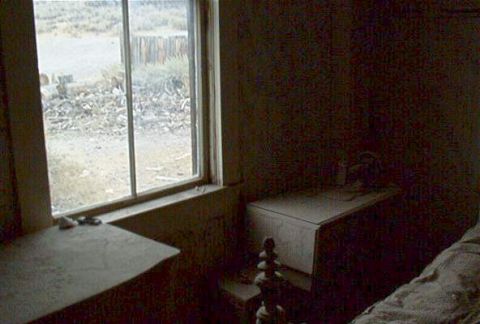 1986 Ford Bronco - A view from inside a rustic building, showing a window with a dusty sill and a glimpse of the outdoors, with a Supermotors logo in the corn…