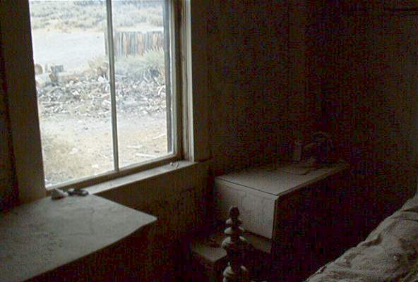 Interior view of a dusty room with a window overlooking a desolate landscape. Supermotors logo visible