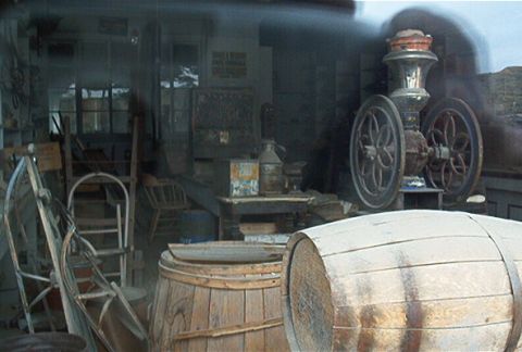 1986 Ford Bronco - Interior of a rustic general store, filled with barrels, chairs, and antique equipment.