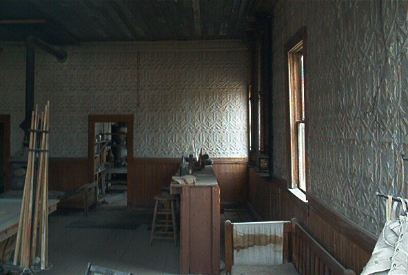 Interior of an old building with patterned walls, a wooden counter, and a stool