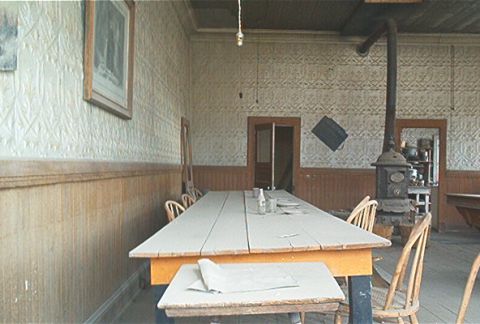 1986 Ford Bronco - A long wooden table is set in a rustic room with a wood-burning stove and vintage decor.