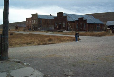 1986 Ford Bronco - A person stands with a tripod in a ghost town, with old wooden buildings in the background.