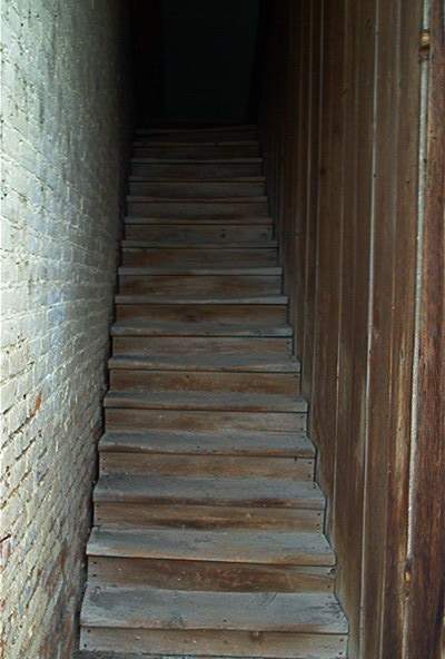 1986 Ford Bronco - A dark wooden staircase ascends between a brick wall and a wood-paneled wall.