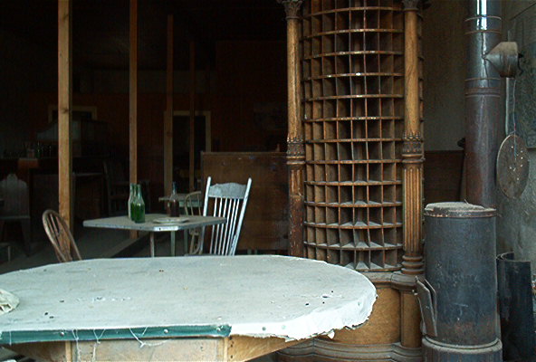 Old building interior with tables, chairs, a wood stove, and a large pigeonhole organizer