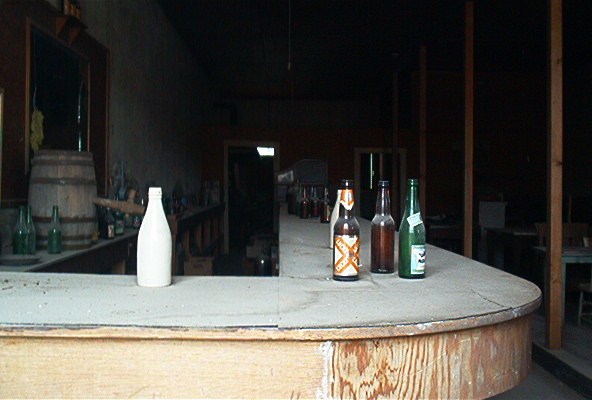 Dusty bar counter with bottles and a barrel