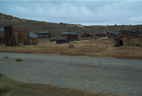 1986 Ford Bronco - A view of an abandoned town with weathered wooden structures under a cloudy sky.
