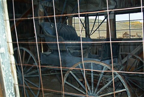 1986 Ford Bronco - This antique carriage is stored inside a barn, with a view of a desolate landscape through the windows.