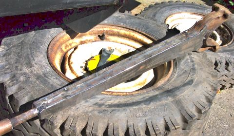 1978 Ford Bronco - A metal component is placed on top of two tires, with visible text on one of the tires.