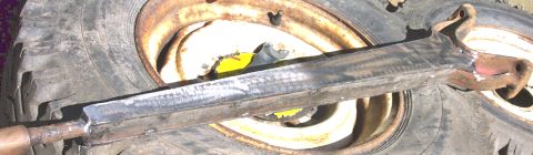 1978 Ford Bronco - A fabricated metal part is placed on top of a worn tire and rusty wheel rim.