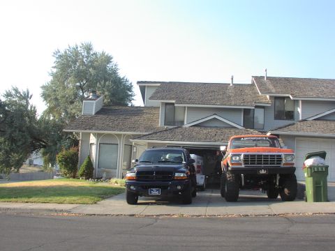 1979 Ford Bronco - A lifted 1979 Ford Bronco pickup truck is parked in front of a house next to a black SUV.