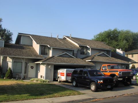 1979 Ford Bronco - Orange pickup truck with black trim parked in front of a house, alongside a dark blue SUV and a U-Haul trailer.