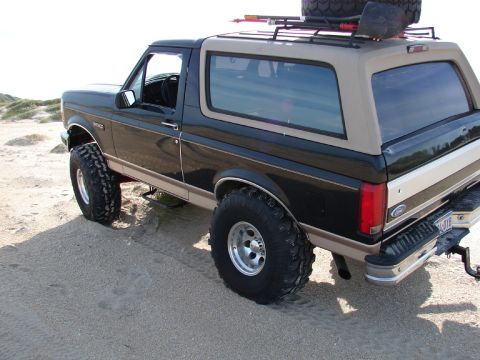 1996 Ford Bronco - This 1996 Ford Bronco, modified for off-road use, is captured in a three-quarter front view on a sandy landscape.