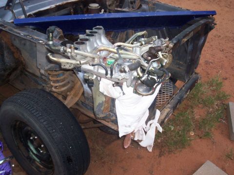 2005 Ford Mustang - The engine compartment of a vehicle is shown with the engine exposed and some components removed.