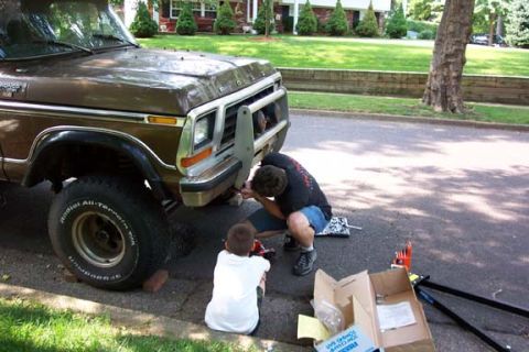 1979 Ford Bronco - A brown 1978 Ford Bronco is being worked on by two people in front of a residential house.