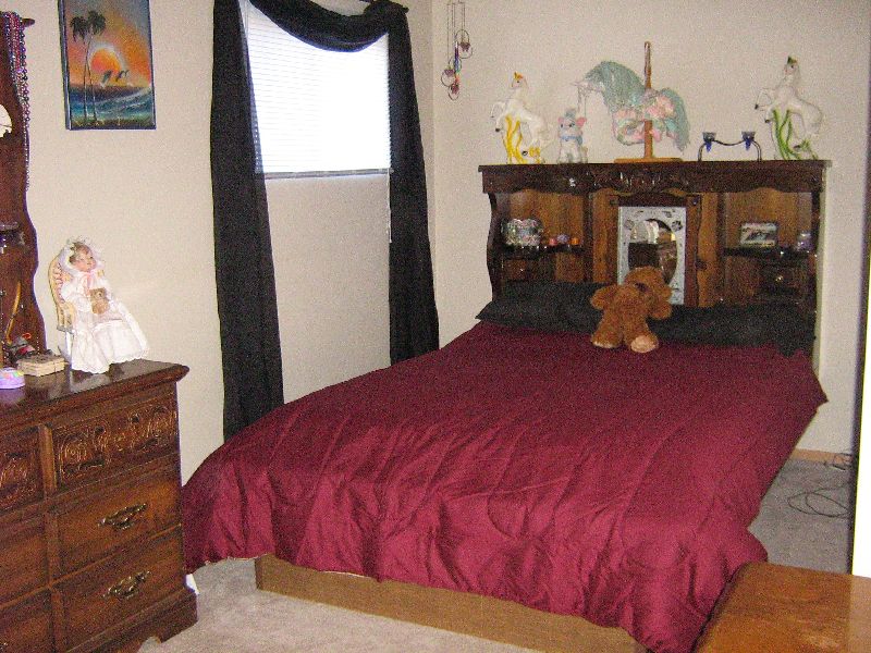 Bedroom with a bed, dresser, and window. A teddy bear sits on the bed