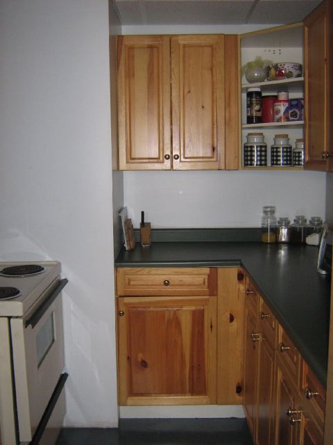 1995 Ford Bronco - Interior view of a kitchen wooden cabinetry, a dark countertop, and a white electric stove.