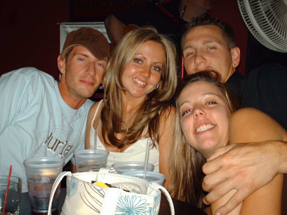 Four people posing for a photo at a table with drinks