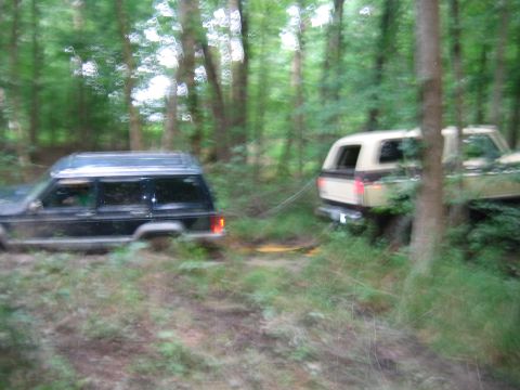 1992 Ford Mustang - Two SUVs are stuck in the woods, one appears to be trying to tow the other out.