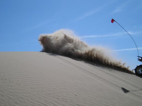 1993 Ford Bronco - An off-road vehicle creates a dust cloud while traversing a sand dune.