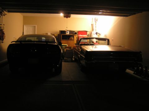 2007 Ford Mustang - An older convertible and a modern coupe are parked side-by-side in a dimly lit garage.