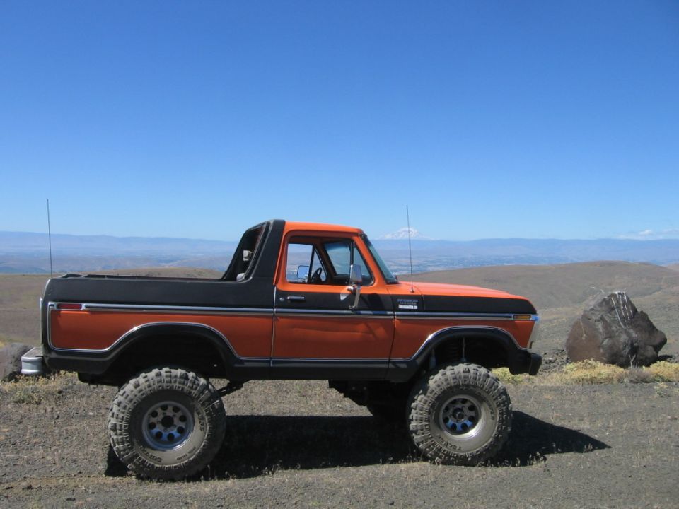 Orange and black lifted Ford Bronco parked on a hill