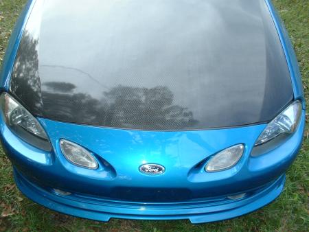 2000 Ford Escort - Front view of a blue car with a carbon fiber hood and a Ford badge, identified as a 2000 Ford Escort.