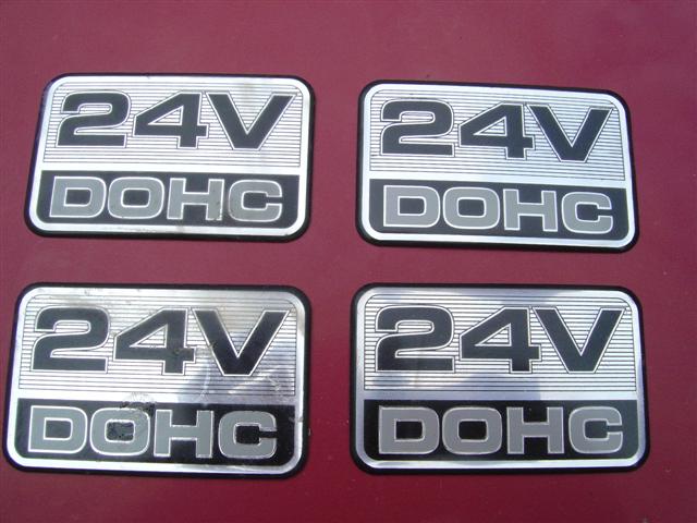 Four 24V DOHC emblems on a red surface
