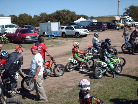1995 Ford Probe - A group of people and dirt bikes are gathered in a pit area, possibly before a race.