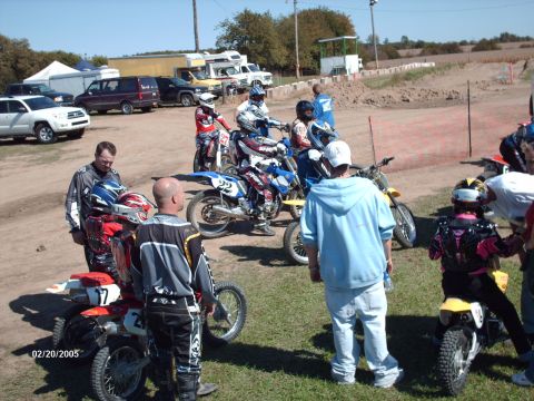 1995 Ford Probe - A group of motocross riders and their bikes are gathered at a track, with vehicles and spectators in the background.