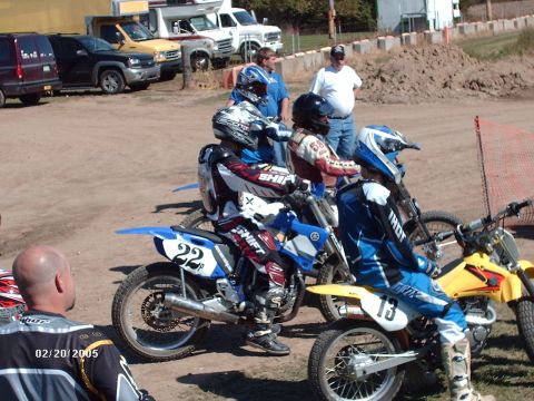 1995 Ford Probe - Motocross riders prepare for a race, with several dirt bikes lined up and spectators in the background.