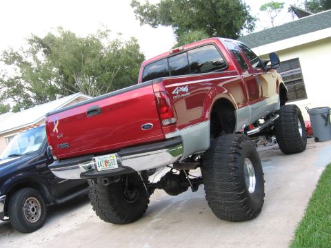 1974 Ford F-100 - Rear view of a heavily modified red pickup truck with large off-road tires.
