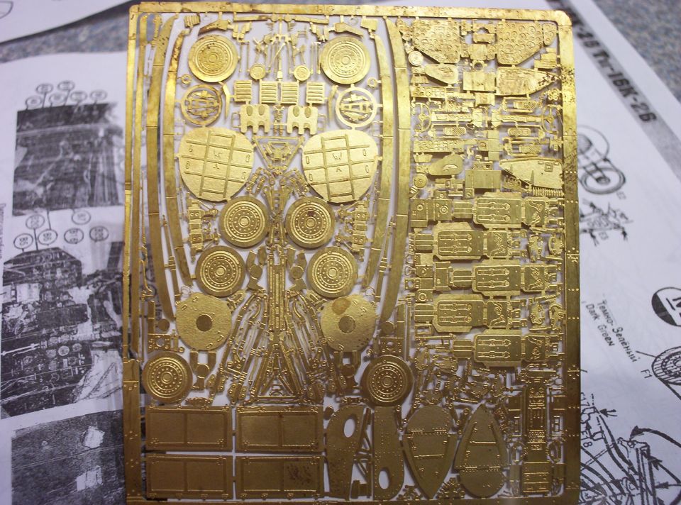 Photo-etched model kit parts on a brass sprue, with instruction sheets visible