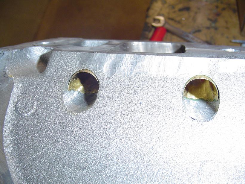 Close-up of a cast metal engine block with two drilled holes
