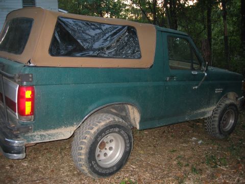 1990 Ford Bronco - This green SUV has a tan soft top and appears to be a Ford Bronco from the early 1990s.