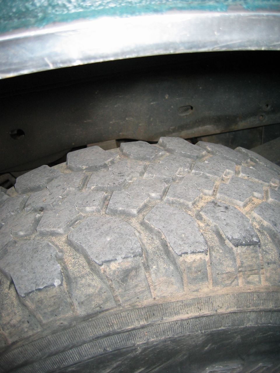 close-up of a knobby off-road tire and the underside of a vehicle's wheel well
