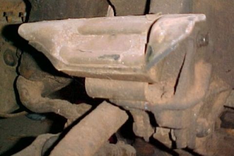 1965 Ford Mustang - Close-up view of a worn engine mount bracket, showing signs of damage and age.
