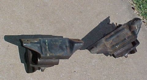 1965 Ford Mustang - A dark-colored engine mount is shown on a concrete surface, with a visible part number stamped on its side.