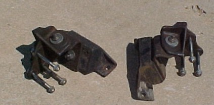 1965 Ford Mustang - Two old engine mounts sit on a concrete surface, showing signs of wear and rust.