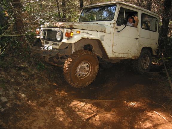 White Toyota FJ40 Land Cruiser on muddy forest off-road trail