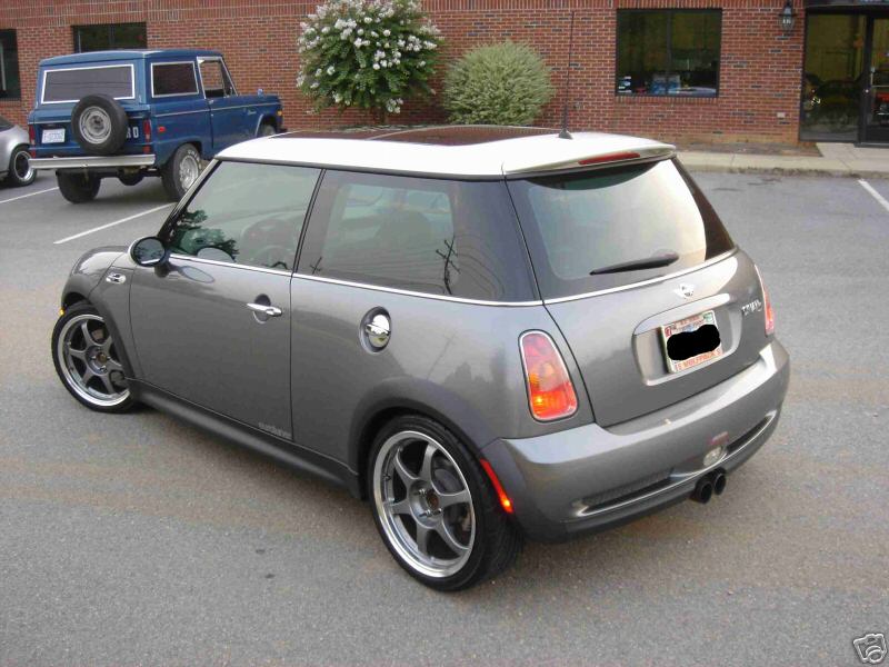 Grey MINI Cooper with white roof, rear 3/4 view, on chrome-lip wheels