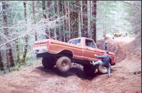 1976 Ford F-100 - Pickup truck driving off-road with another vehicle visible in the background.
