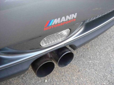 2003 MINI Cooper - Close-up of a vehicle's rear bumper, showing dual exhaust pipes and a "MANN MOTORSPORTS" decal.