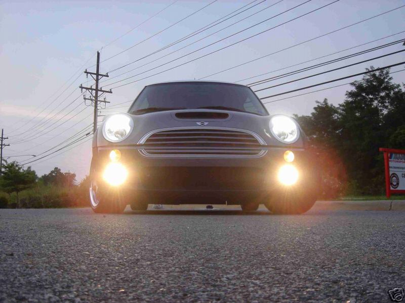 Silver MINI Cooper front view at dusk, headlights and fog lights on, shot low to the ground