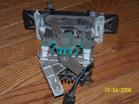1979 Ford F-150 - A disassembled heater control unit with visible levers and electrical connectors is shown on a wood floor.