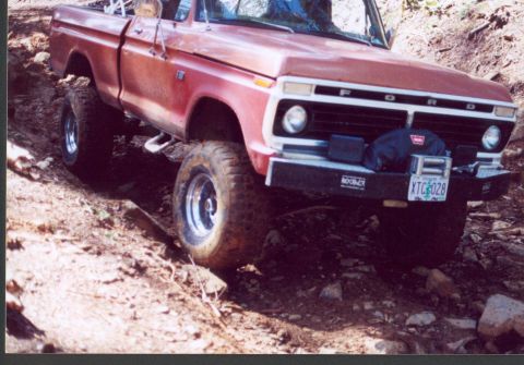 1976 Ford F-100 - This red Ford F-100 navigates a rough, off-road terrain with its front end angled towards the viewer.