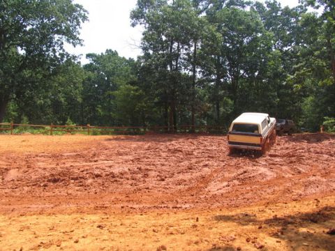 1992 Ford Mustang - A yellow and white truck navigates a muddy terrain, with another vehicle visible behind it.